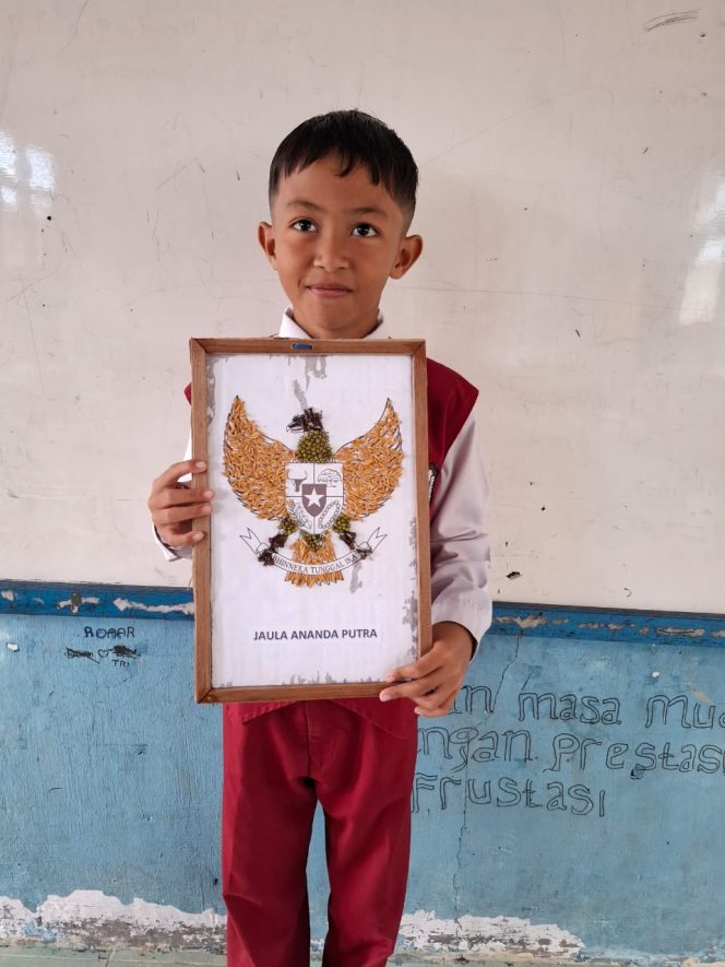 
					Jaula Ananda Putra menunjukkan hasil karya kolase berbahan biji-bijian dan daun kering yang mengantarkannya meraih penghargaan tugas mandiri dari pihak sekolah, Senin(8/12). 