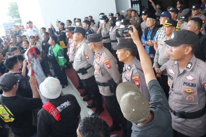 
					Petugas kepolisian berjaga saat aksi penyampaian aspirasi pengemudi transportasi online di halaman Kantor Gubernur Kepulauan Riau, Dompak, Tanjungpinang, Rabu (20/5/2026). Aksi berlangsung tertib dengan pengawalan aparat.