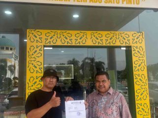 Ketua GAMNR Kota Tanjungpinang, Said Ahmad Syukri (kiri), didampingi Humas GAMNR, Riswandi (kanan), menunjukkan surat laporan usai diserahkan di Pelayanan Terpadu Satu Pintu (PTSP) Kejaksaan Tinggi Kepulauan Riau, Senin (25/5/2026). Laporan tersebut terkait pengadaan pakaian dinas di BKAD Provinsi Kepulauan Riau.