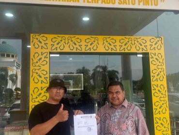 Ketua GAMNR Kota Tanjungpinang, Said Ahmad Syukri (kiri), didampingi Humas GAMNR, Riswandi (kanan), menunjukkan surat laporan usai diserahkan di Pelayanan Terpadu Satu Pintu (PTSP) Kejaksaan Tinggi Kepulauan Riau, Senin (25/5/2026). Laporan tersebut terkait pengadaan pakaian dinas di BKAD Provinsi Kepulauan Riau.