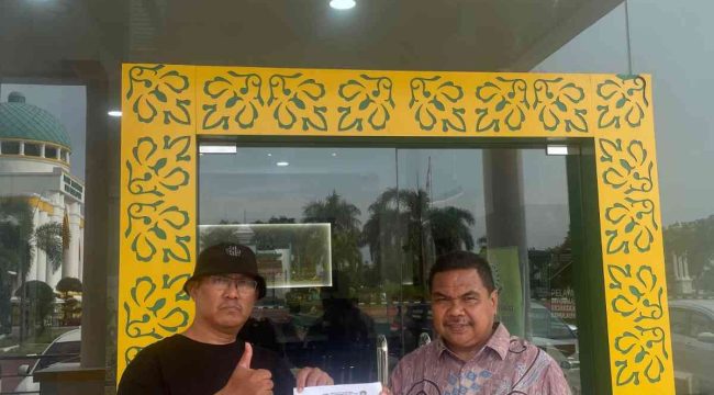 Ketua GAMNR Kota Tanjungpinang, Said Ahmad Syukri (kiri), didampingi Humas GAMNR, Riswandi (kanan), menunjukkan surat laporan usai diserahkan di Pelayanan Terpadu Satu Pintu (PTSP) Kejaksaan Tinggi Kepulauan Riau, Senin (25/5/2026). Laporan tersebut terkait pengadaan pakaian dinas di BKAD Provinsi Kepulauan Riau.