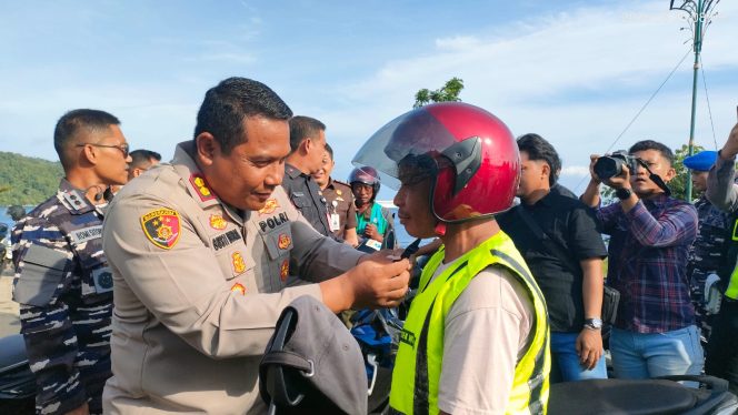 
					Kapolres Kepulauan Anambas AKBP Gogot Suharjono memasangkan helm kepada salah seorang pengendara saat kegiatan pembagian 50 helm gratis di Astaka Masjid Agung Baitul Ma'mur, Tarempa, Kamis (25/6/2026).